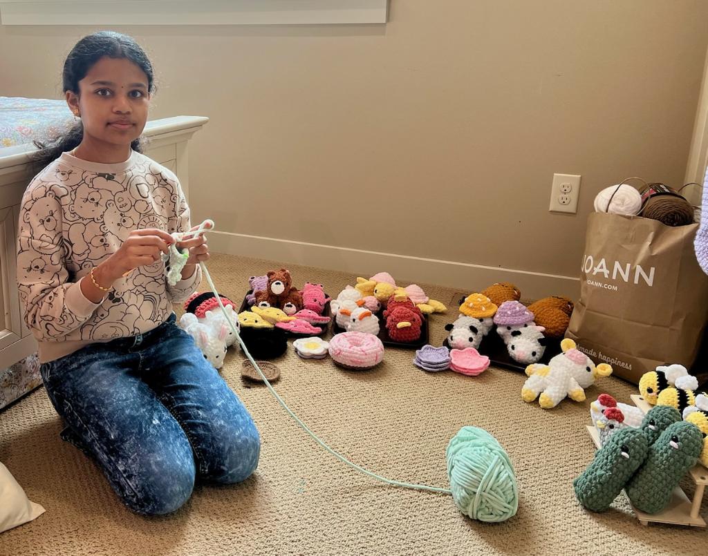 Samy crocheting surrounded by her plushies